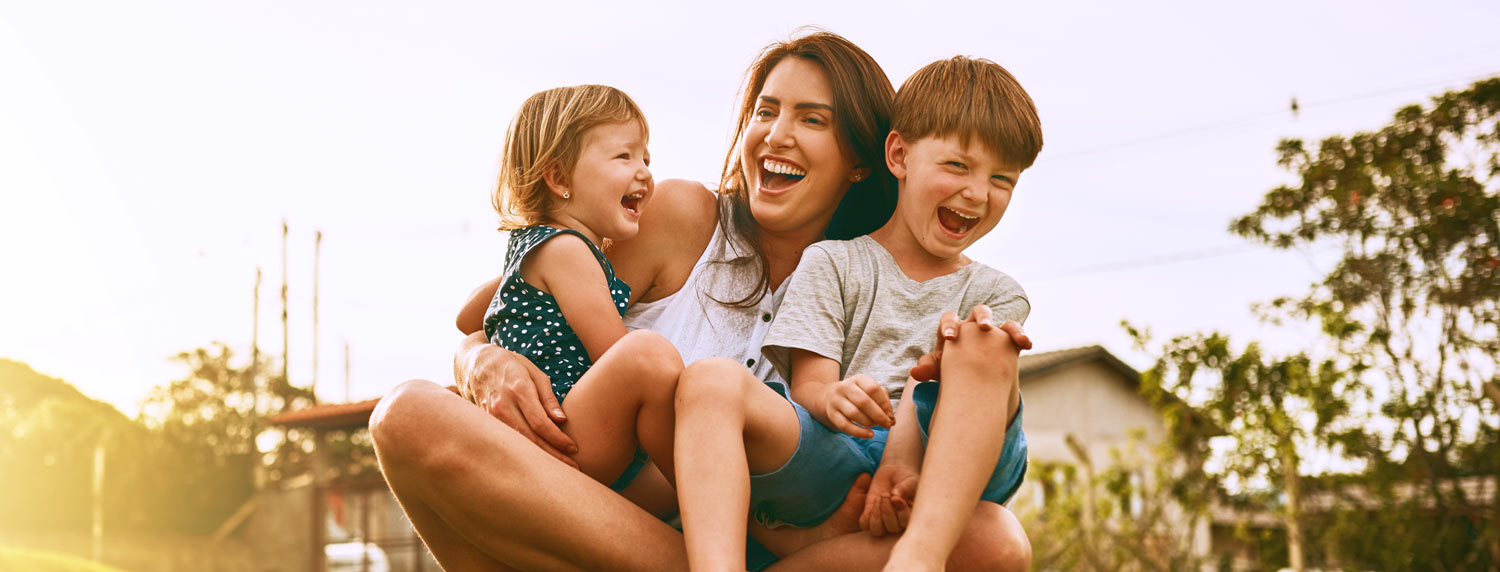 Photo of a mum and her two kids, smiling outside
